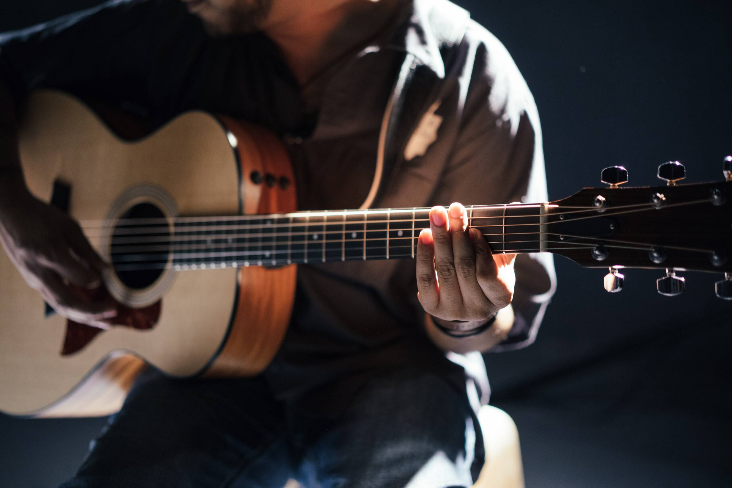A seated person playing acoustic guitar